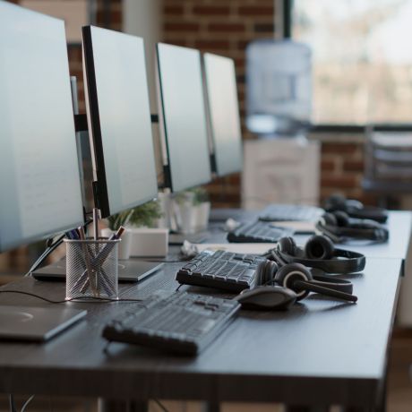 Empty customer service workstation to help telemarketing clients, modern call center technology for sales assistance and support. No people in office with monitors and headphones.